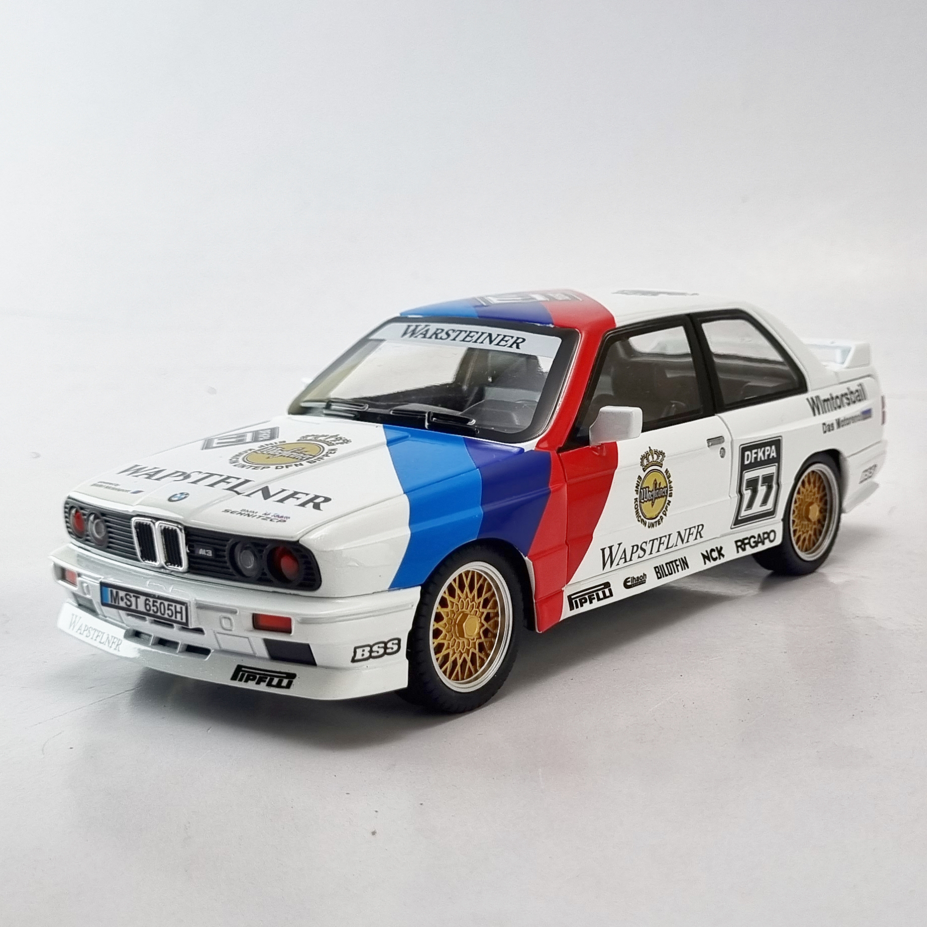 GridArt_20250517_182236180 "نمای جلویی مدل دایکست BMW M3 E30 Warsteiner در مقیاس 1:24، با تأکید بر جزئیات خارجی و برند Warsteiner."