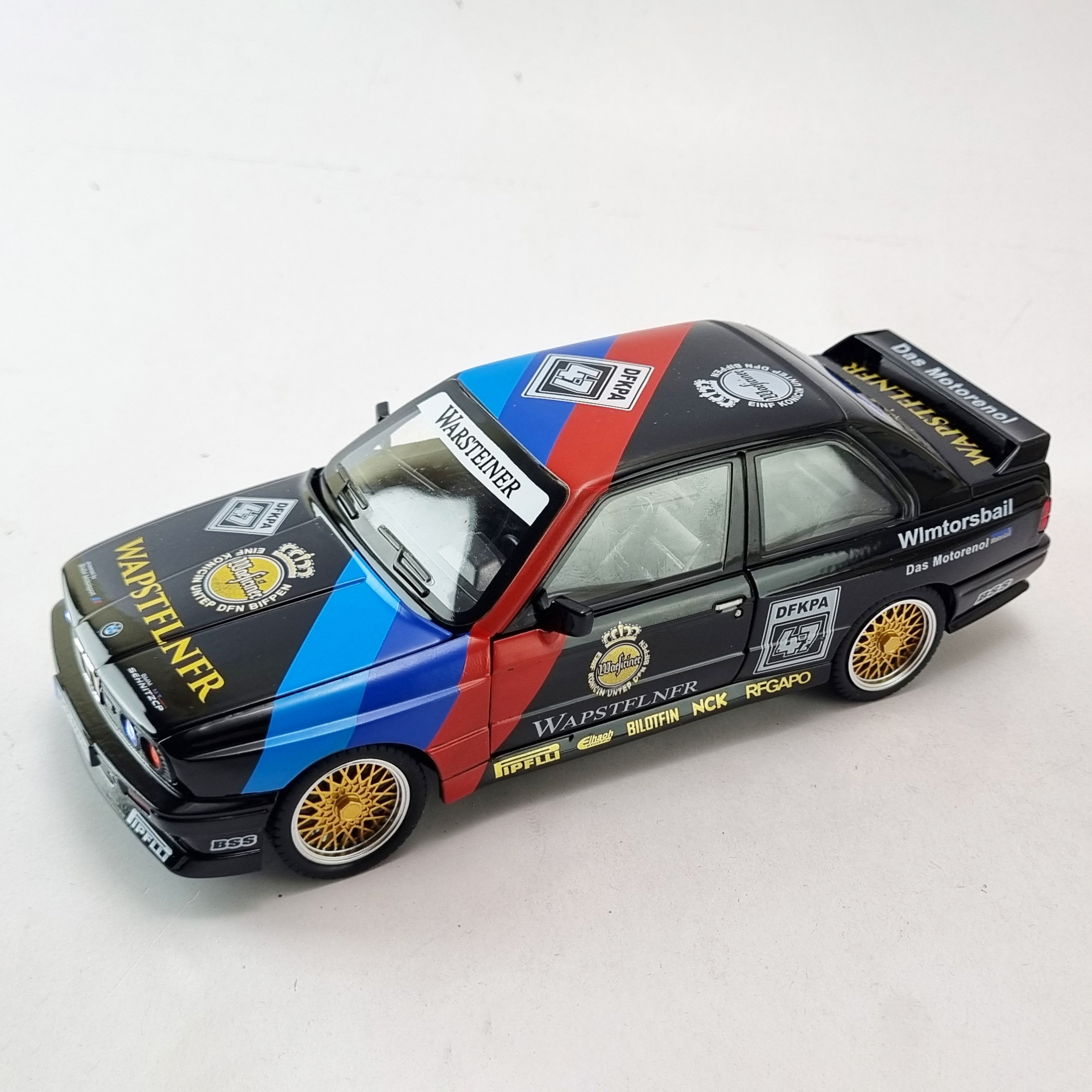 GridArt_20250517_182644873 "نمای بالای مدل دایکست BMW M3 E30 Warsteiner با کابین باز، که جزئیات داخلی و طرح Warsteiner را نشان میدهد."