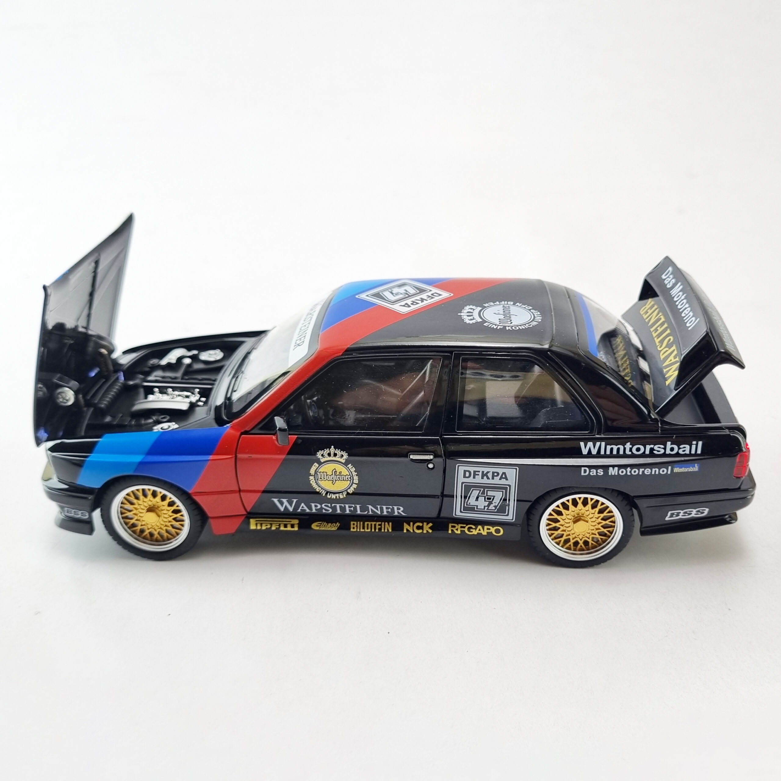 GridArt_20250517_182755792 "مدل دایکست BMW M3 E30 Warsteiner با کاپوت باز، که موتور دقیق و طرح Warsteiner را به نمایش میگذارد."